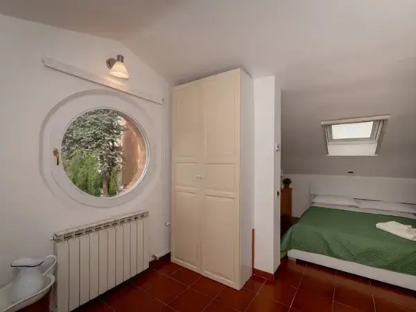 Terza camera da letto con finestra rotonda nella mansarda della villa.