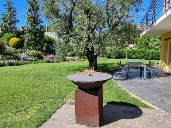 Zona da pranzo esterna nel giardino e coperta, con tavolo da pranzo e barbecue.